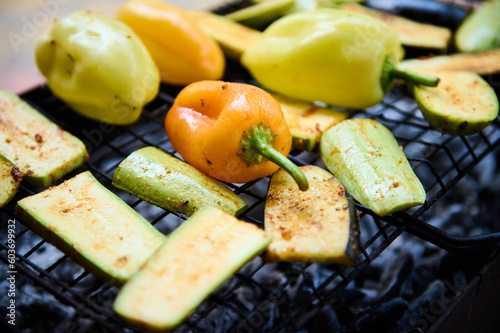 Selective focus on grilled bell pepper and sliced zucchinis over charcoal in the barbecue grill. Close-up. The concept of summer and weekend outdoors leisures. Picnic in the nature or backyard