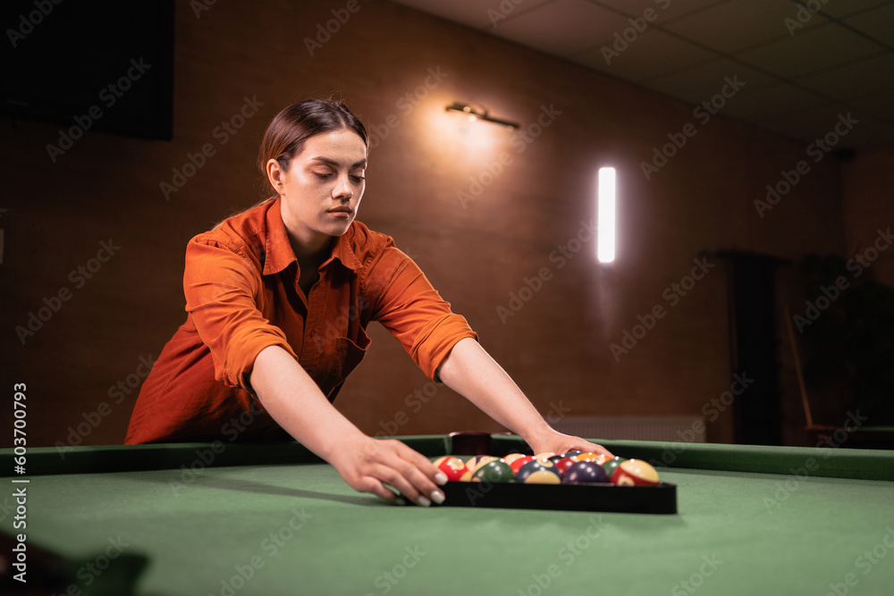 Young woman put billiard balls pool in triangle on green table, game. Ball, snooker, billiard and pool Young woman put billiard balls pool in triangle on green table, game. Ball, snooker, billiard and pool