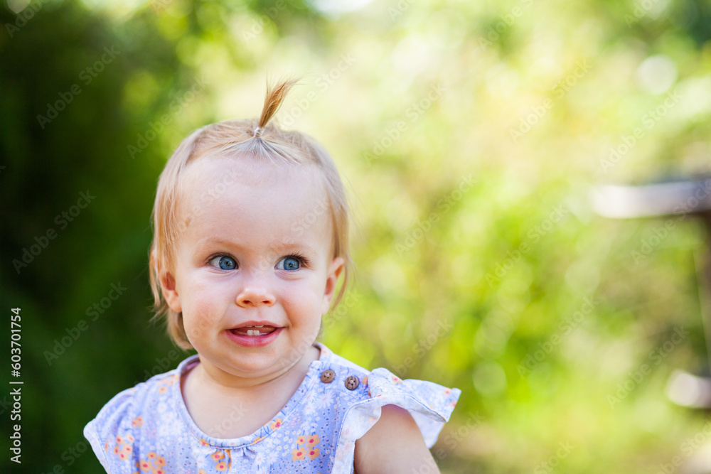 Baby girl against green backdrop outside with hair in topknot crest Baby girl against green backdrop outside with hair in topknot crest
