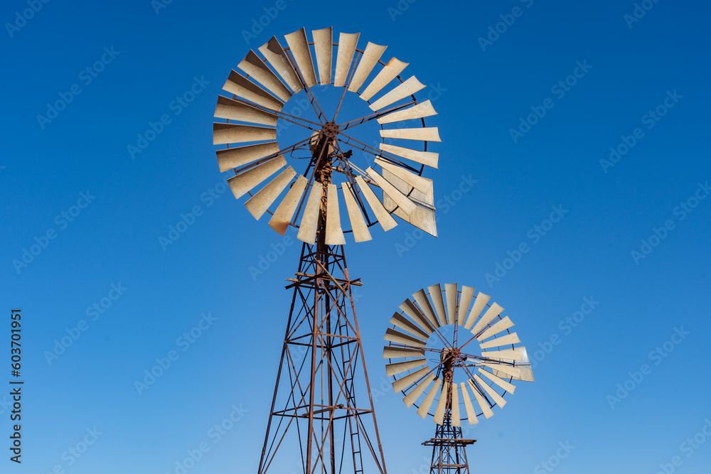 Looking up at wo large windmills against a blue cloudless sky Looking up at wo large windmills against a blue cloudless sky