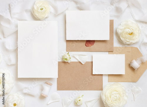 Blank cards and envelopes near cream roses and white ribbons top view, wedding mockup