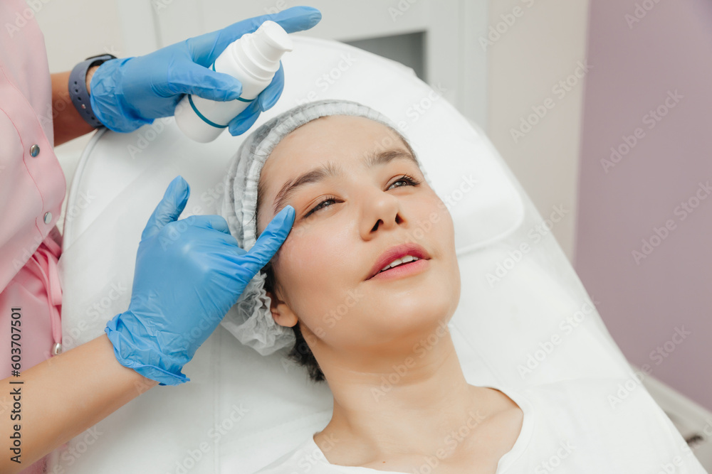 Beautician's hands apply cream on woman's forehead. Skin treatment. Spa beauty treatments. cream after botoxre Beautician's hands apply cream on woman's forehead. Skin treatment. Spa beauty treatments. cream after botoxre
