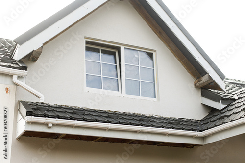 Canvas Print Modern farmhouse exterior with stylish black roof, white walls and windows, dormer and wooden rafters