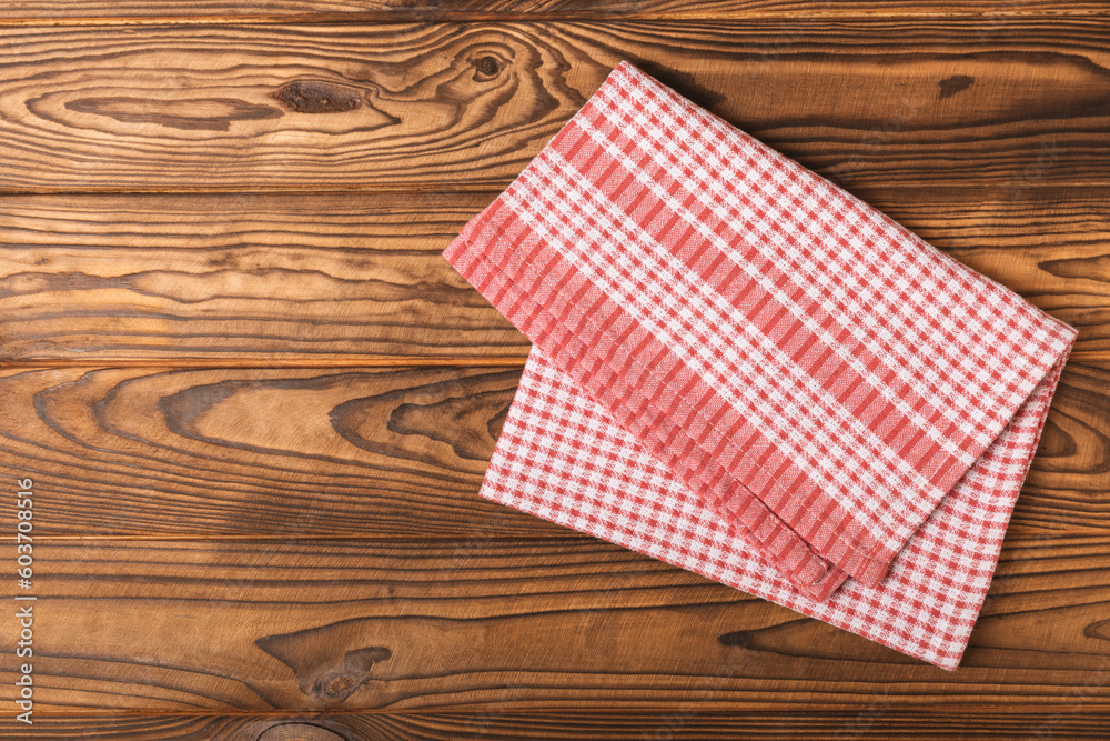 Checkered kitchen cotton towels folded on a brown texture table. Kitchenware. Kitchen towel or textile napkin. Copy space for text. Place for text. Tablecloth. Checkered kitchen cotton towels folded on a brown texture table. Kitchenware. Kitchen towel or textile napkin. Copy space for text. Place for text. Tablecloth.