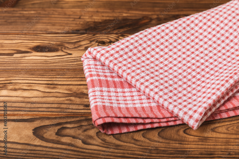 Checkered kitchen cotton towels folded on a brown texture table. Kitchenware. Kitchen towel or textile napkin. Copy space for text. Place for text. Tablecloth. Checkered kitchen cotton towels folded on a brown texture table. Kitchenware. Kitchen towel or textile napkin. Copy space for text. Place for text. Tablecloth.