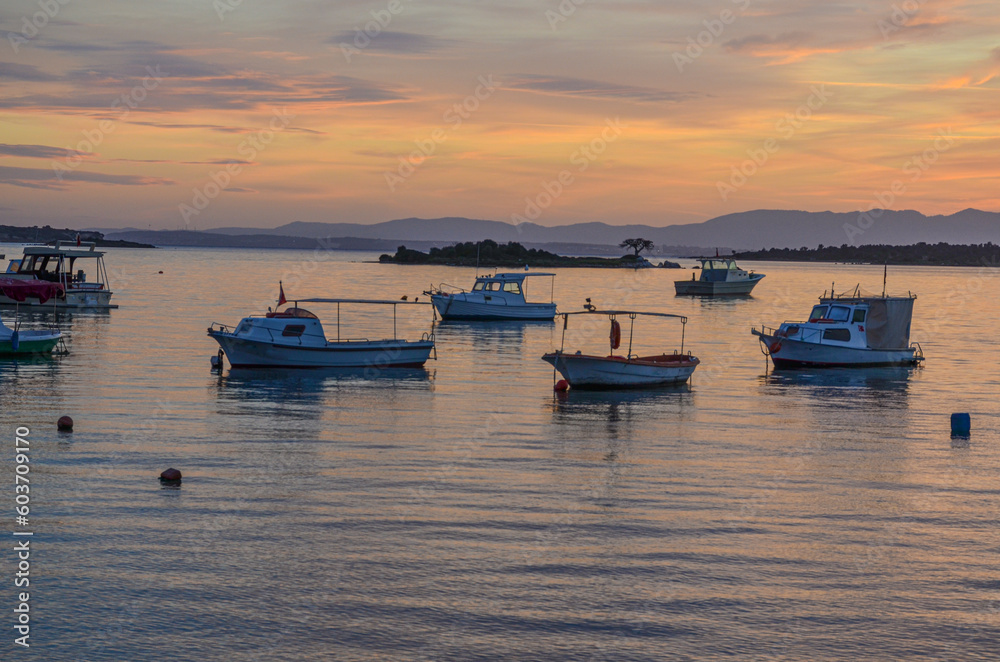 fishing boats and Zeki Muren island in Ildir Bay harbor at sunset (Cesme, Izmir province, Turkiye) 