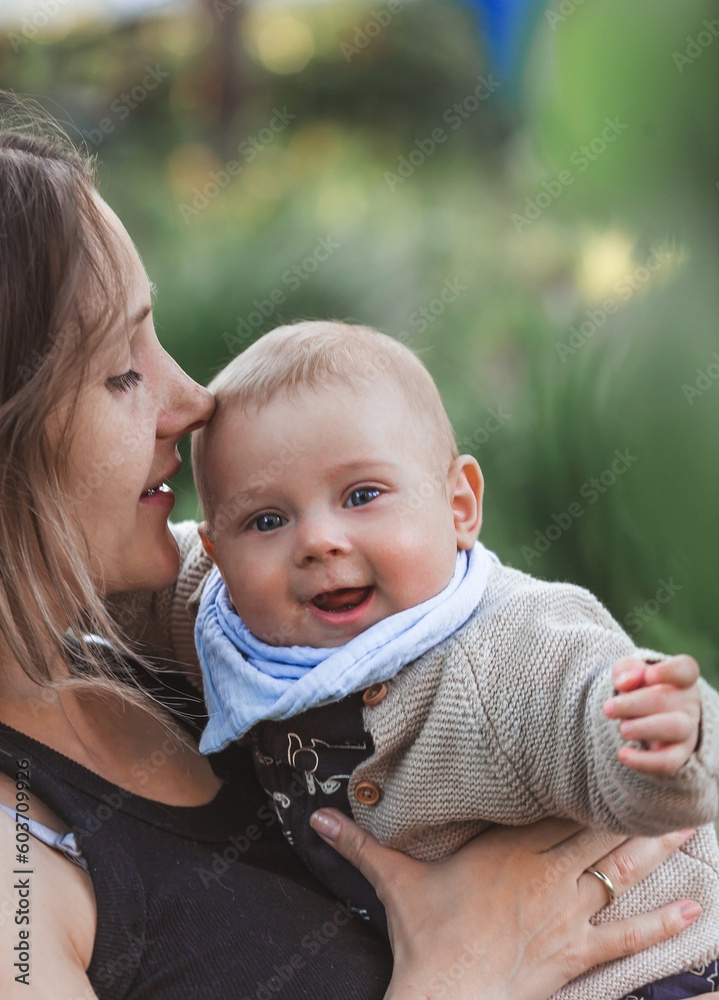 Charming smiling boy in nature in the arms of his mother. A child of 4 months plays with his mother and smiles. Family, pregnancy and childbirth. Charming smiling boy in nature in the arms of his mother. A child of 4 months plays with his mother and smiles. Family, pregnancy and childbirth.