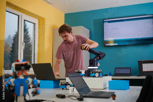 A student testing his new invention of a robotic arm in the laboratory, showcasing the culmination of his research and technological prowess.