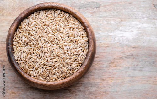 oat seeds in a wooden plate on wooden background top view. Closeup seeds