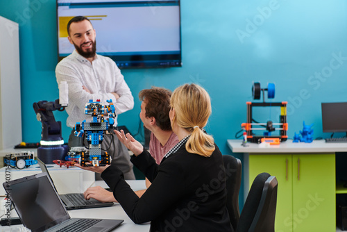 A group of colleagues working together in a robotics laboratory, focusing on the intricate fields of robotics and 3D printing. Showcase their dedication to innovation, as they engage in research