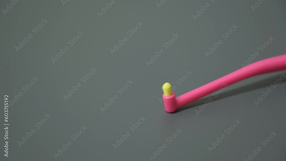 Plastic toothbrush on grey background. Yellow and pink color brush. Healthcare, hygiene for teeth.