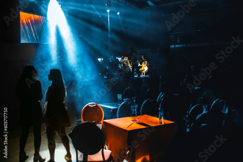Two young girls dance to music of an orchestra in bright light of beams of the stage spotlights