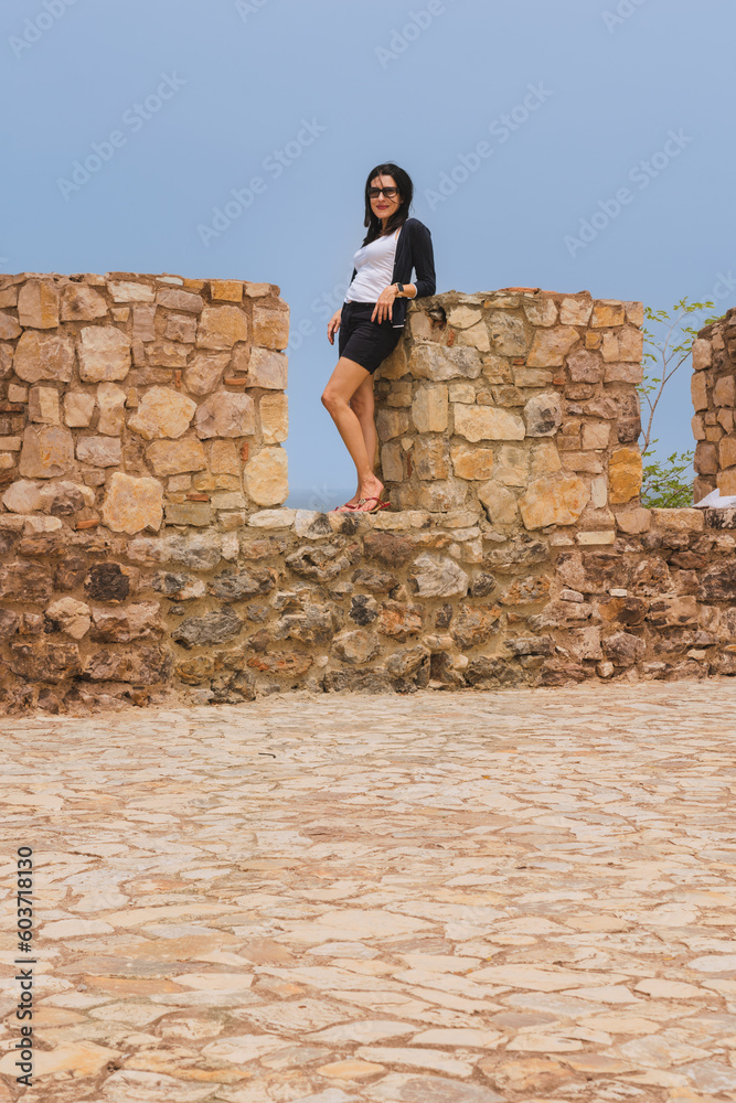 Amateur model posing naturally in a fortress., mature woman, posing in an ancient fortress where you can see its walls and stone floors and the blue sky. Dressed casually on a sunny day