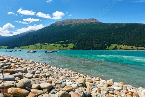 Lifeboats on the shore for personal rescue and training purposes. Watercraft in front of beautiful mountain landscape in the lake (Reschensee). Italy, Vinschgau.