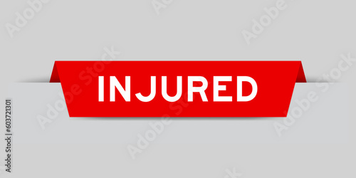 Red color inserted label with word injured on gray background