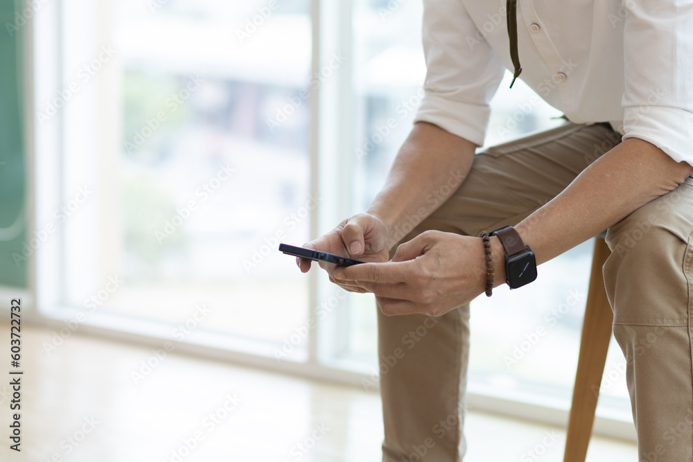 Businessman sitting in a chair in the office is using a smartphone. Businessman sitting in a chair in the office is using a smartphone.