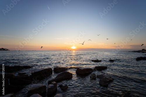 Fototapeta Naklejka Na Ścianę i Meble -  Scenic sunset at Porec beach, Croatia, flying birds