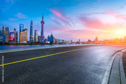 Asphalt road and city skyline with modern buildings at sunset in Shanghai, China.