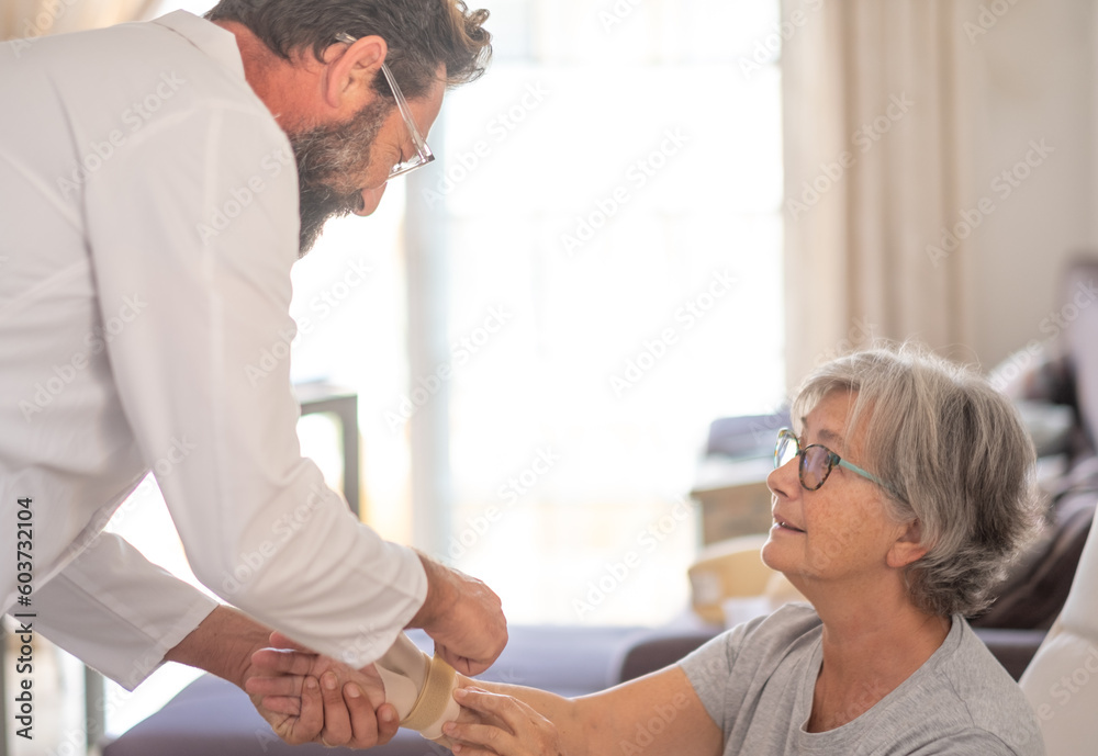 Physiotherapist visiting a senior patient with right thumb osteoarthritis helping her to put on a thumb splint. Pain and rehabilitation of the elderly woman