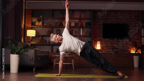 Yoga at home. The gray-haired man does yoga at home, doing asanas. Sports, stretching, gymnastics of an elderly man. Healthy lifestyle in old age.