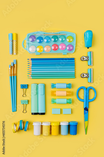 Various colorful material for creativity and art activity is arranged neatly on yellow background.  Stationery and supplies for drawing and craft. Workplace organization.
