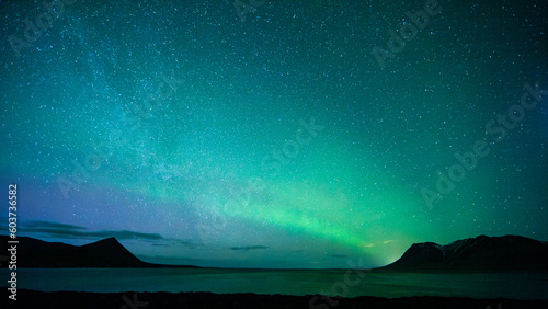 Fotografie Green sky of Northern Lights above sea and hills in Iceland