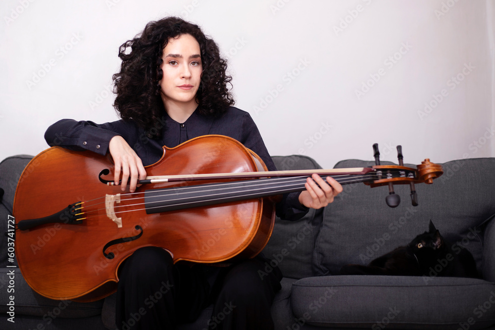 Female musician playing cello while sitting on sofa Female musician playing cello while sitting on sofa