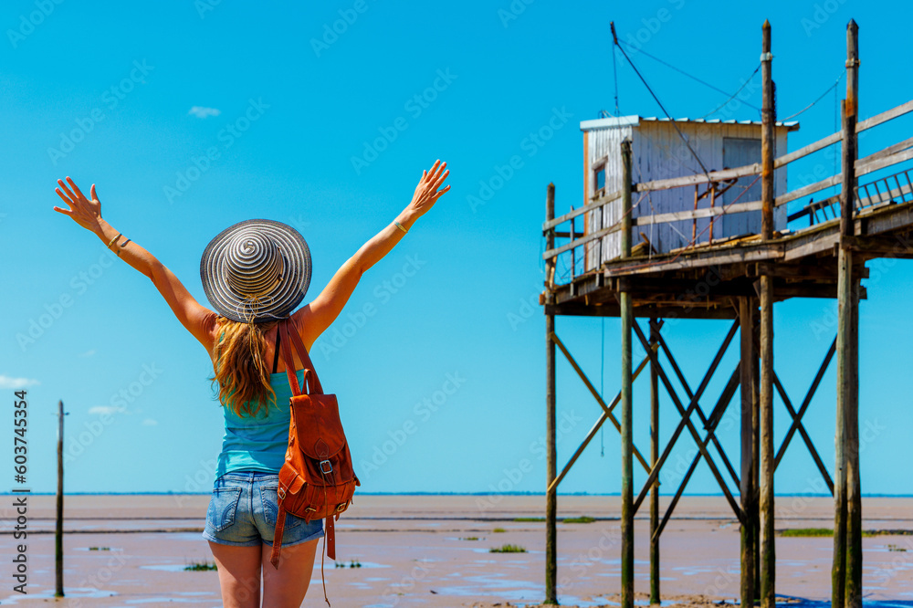 Happy woman enjoying view of traditional carrelet ( traditional fishing hut)- Charente Maritime- Tour tourism in France - obrazy, fototapety, plakaty 