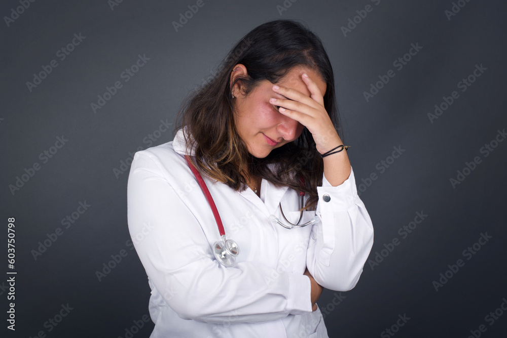 Indoor portrait of beautiful woman with stylish haircut, wearing casual clothes, making facepalm gesture while smiling, standing over gray background amazed with stupid situation. Indoor portrait of beautiful woman with stylish haircut, wearing casual clothes, making facepalm gesture while smiling, standing over gray background amazed with stupid situation.