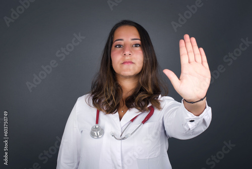 Young beautiful caucasian woman doing stop gesture with palm of the hand. Warning expression with negative and serious gesture on the face isolated over gray background.