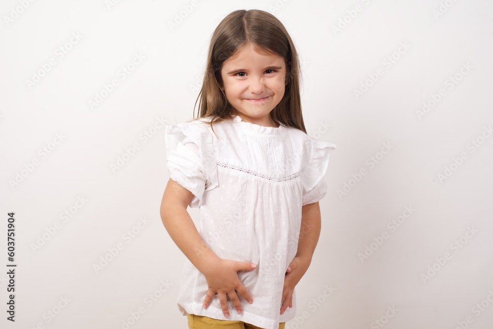 Cute charming little girl wearing white shirt over white background smiling and looking to the camera, feeling confident and happy. Cute charming little girl wearing white shirt over white background smiling and looking to the camera, feeling confident and happy.