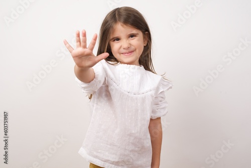 Cute charming little girl wearing white shirt over white background pointing up with fingers number five or making stop gesture. Girl making high five 