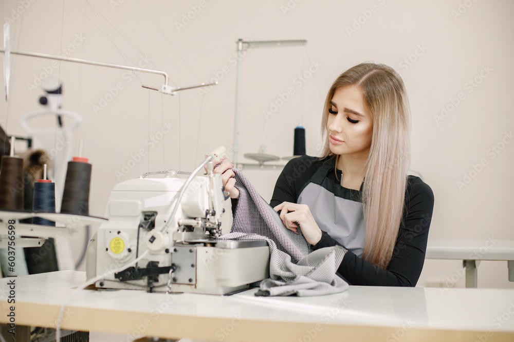 Young seamstress sitting on the sewing machine in her workshop Young seamstress sitting on the sewing machine in her workshop