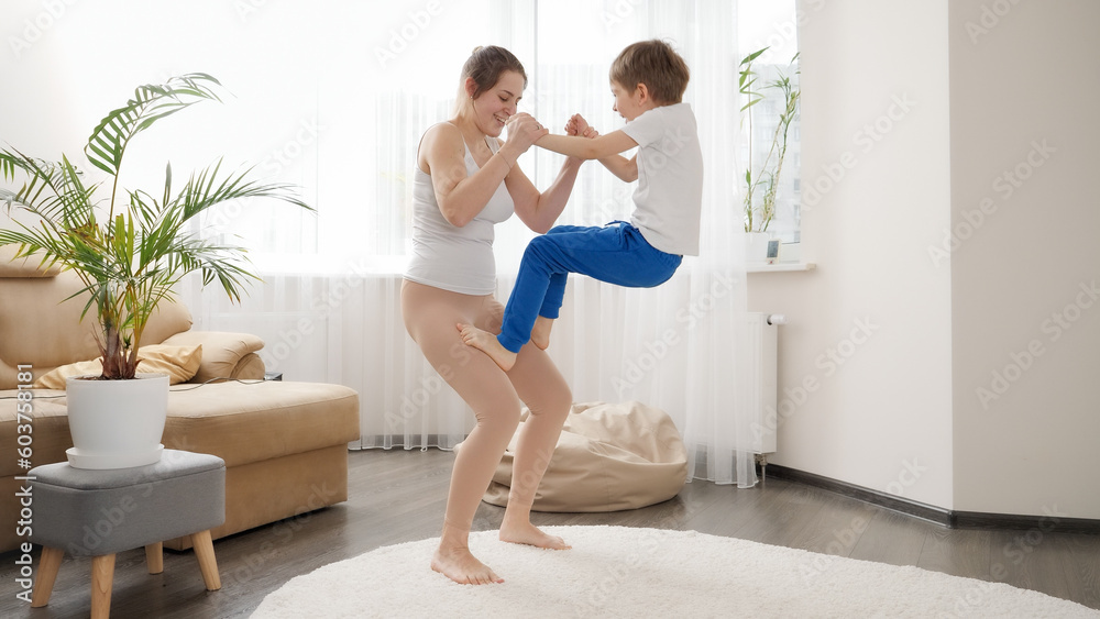 Happy mother holding her son while he is climbing up on her. Family healthcare, active lifestyle, parenting and child development Happy mother holding her son while he is climbing up on her. Family healthcare, active lifestyle, parenting and child development