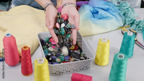 The girl acquires in both hands a lot of buttons from a plastic box. photo