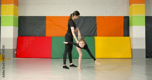 Girl gymnast practice with a trainer in a studio