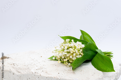 Bouquet of lilies of the valley on white stone with writing space on white background, suitable for greeting message