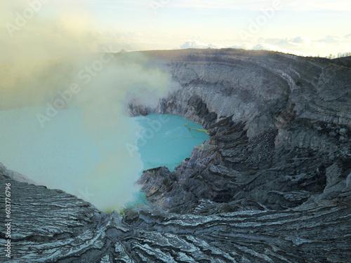 Wulkan Ijen z błękitnym jeziorem kwasu siarkowego w kraterze z którego wydobywa się płynna siarka i toksyczne opary gazu siarkowego