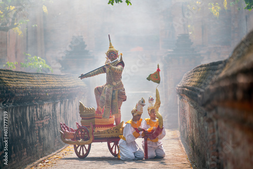 Khon or traditional Thai classic masked from the Ramakien as character of red giant stand and dance on traditional chariot also hold weapon stay in front of ancient building with mist or fog.
