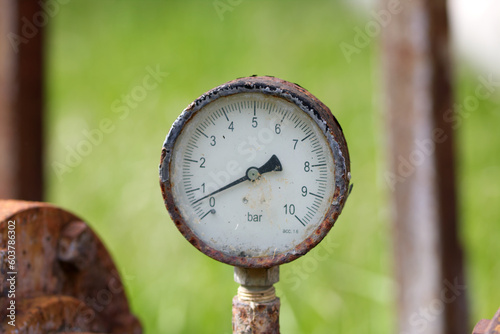 Close up of manometer measuring water pressure. Pipes and valves at industrial plant.