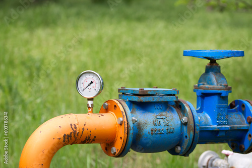 Close up of manometer measuring water pressure. Pipes and valves at industrial plant.