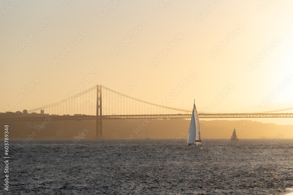 Obraz premium Leisure sailing yacht heading into Lisbon harbour at sunset