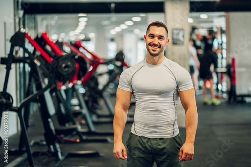 Portrait of a happy sportsman with big muscles standing in a gym and smiling at the camera.