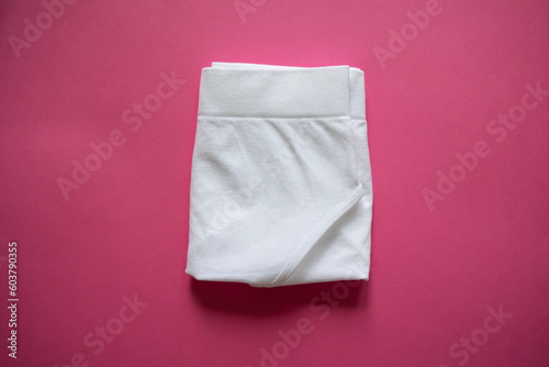 Folded white panties on a pink background. Step 4. Storage by method, organization, closet, underwear, minimalist briefs. Step-by-step folding of panties. Mockup. Briefs. Stacked cotton underwear