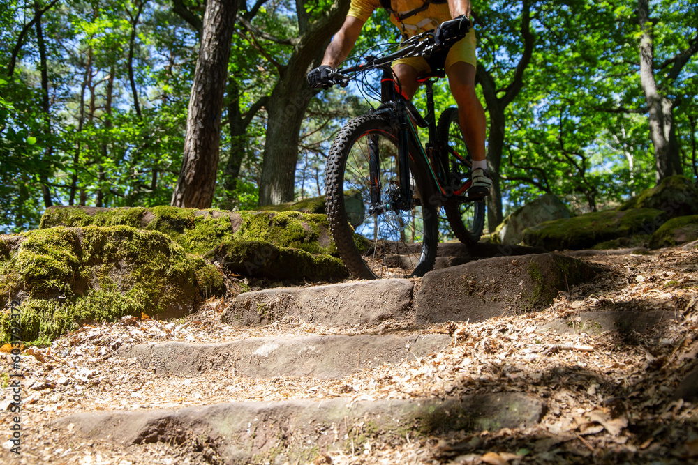 Mountainbiker fährt einen schwierigen Singletrail mit mehreren Stufen Mountainbiker fährt einen schwierigen Singletrail mit mehreren Stufen