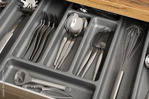 Open kitchen drawer with different silver cutlery, closeup