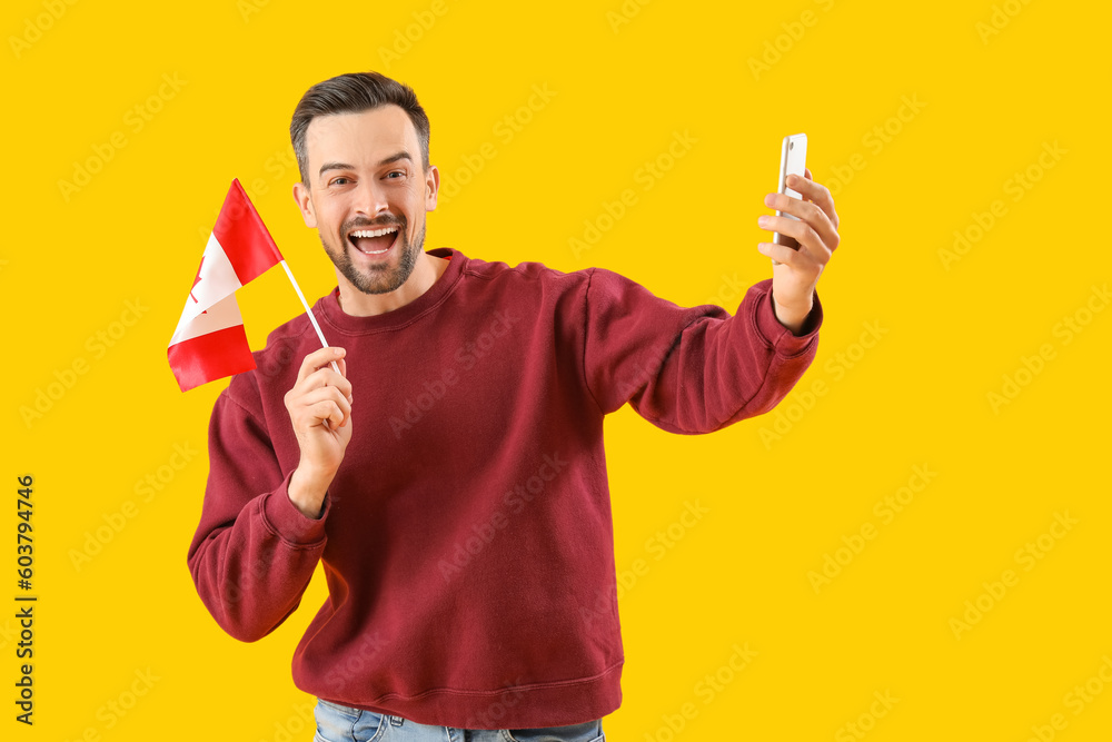 Handsome man with flag of Canada taking selfie on yellow background Handsome man with flag of Canada taking selfie on yellow background