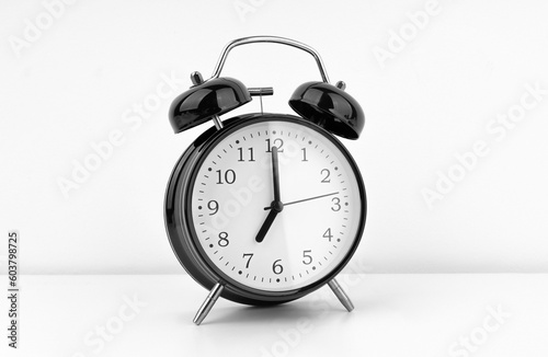 Black alarm clock on white wall background