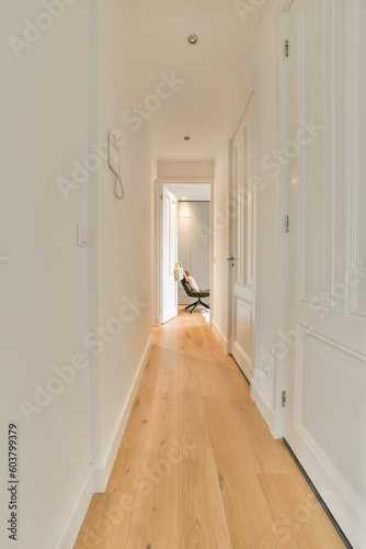 a long hallway with white walls and wood flooring on either side by side  leading to the front door