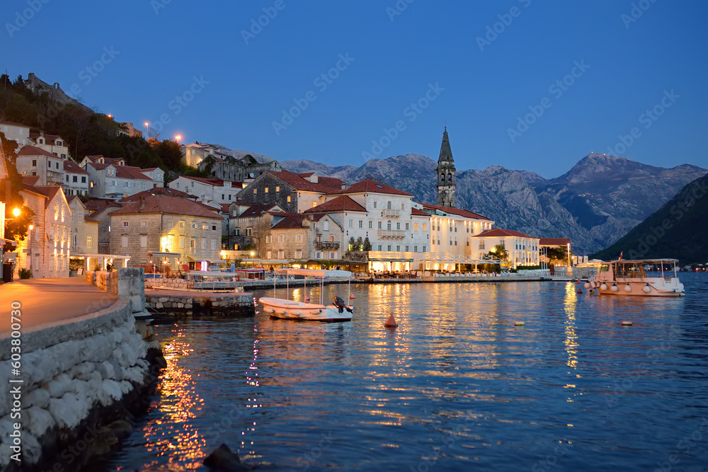 View of ancient picturesque city of Perast, Montenegro. Old medieval little town with red roofs and mountains on background of famous Kotor bay of Adriatic sea at blue hour. Travel and torism